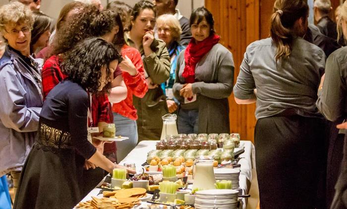 Delegates getting food from a self-serivce buffet of cheese and desserts.